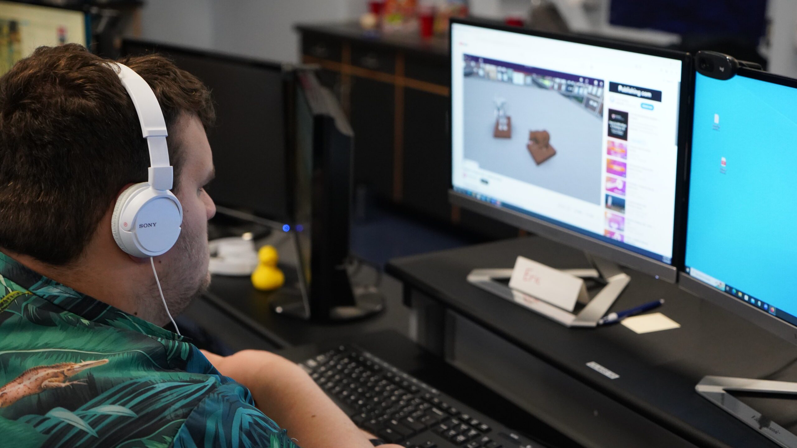 A high school student wearing white headphones and looking at a computer screen that shows a CoSpaces window